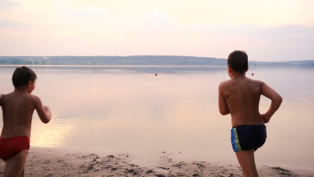 Silhouette of two boys running into the water