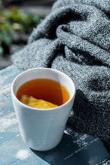 Close up white cup of lemon tea wrapped in blanket