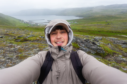 Tourist man making selfie on hill near Skarsvag (near Nordkapp). Landmark on Lofoten islands. Norway.