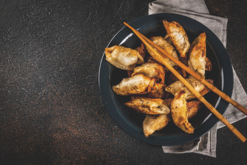 Fried asian dumplings Gyoza  on dark plate, served with chopsticks and soy sauce, dark background, copy space