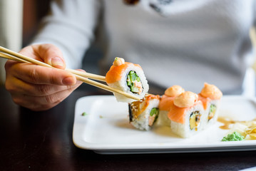 Young woman eats sushi rolls with chopsticks