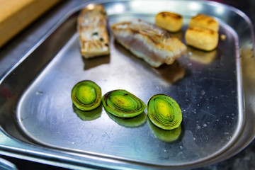 Fish steak with vegetables on metal tray
