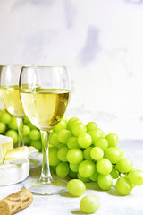 Two glasses of white wine,cheese and grapes.