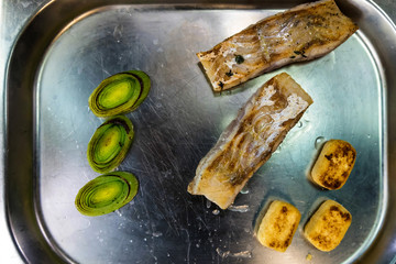 Fish steak with vegetables on metal tray