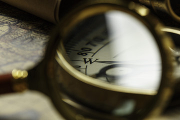 Retro compass with old map and magnifier