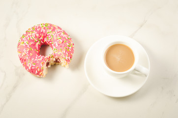 Coffee break with bitten donut/Coffee break with bitten donut on a white marble background. Top view