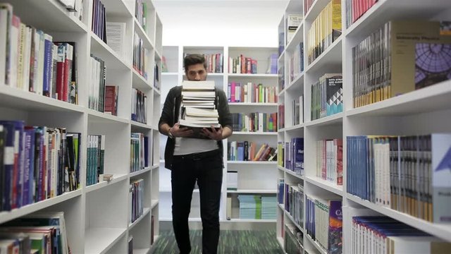Student holding lot of books in school library. Hard worke  concept.