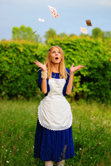 Beautiful young woman dressed in costume throwing playing cards into the air