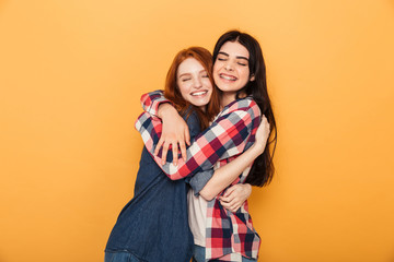 Portrait of two delighted young teenage girls hugging