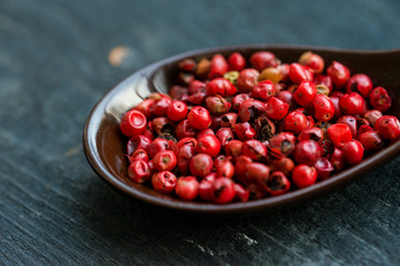 Close up pink peppercorn in spoon dark background