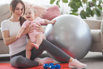 Young pretty mother working out with her little child at home