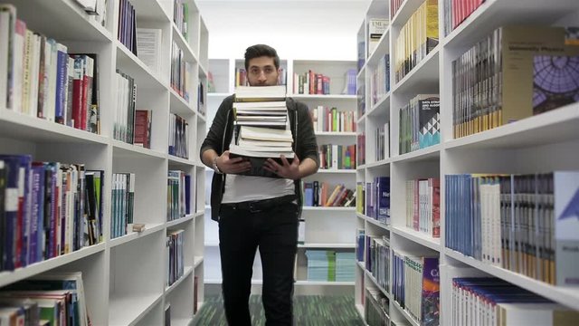 Student holding lot of books in school library. Hard worke  concept.