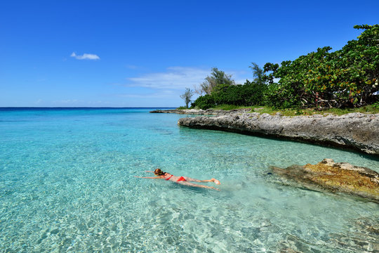 Tourist swimming in turquoise waters of the Caribbean sea on the wild noon coast of Cuba