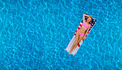 Woman in bikini on the inflatable mattress in the swimming pool.