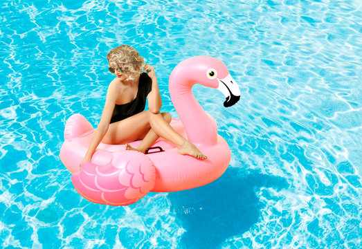 Woman in bikini on the inflatable mattress in the swimming pool.