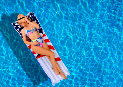 Woman in bikini on the inflatable mattress in the swimming pool.