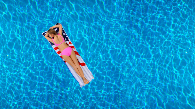 Woman in bikini on the inflatable mattress in the swimming pool.