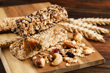 Bunch of mixed gluten free granola energy bars with dried fruit & various nuts, wooden background. Healthy vegan super food, different fitness diet snacks for sporty lifestyle. Top view, copy space.