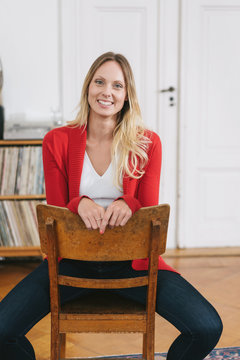Smiling woman with red cardigan sitting on chair