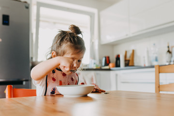adorable toddler girl eating soup at the modern open kitchen