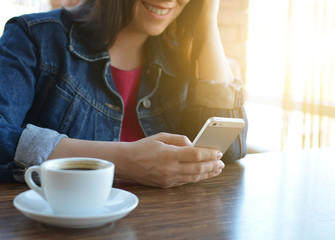 A brunette girl in a denim jacket is eating lunch in a cafe and using her phone. Communication through messenger. Casual loose clothing.