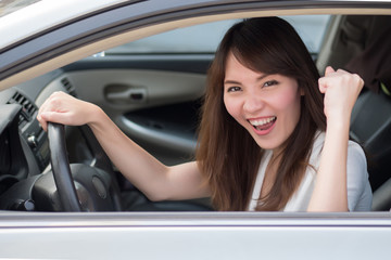 Obraz na płótnie Canvas excited woman driver driving personal car; portrait of happy, smiling, excited asian woman driver driving her car, right hand driving or right hand traffic style; 30s adult asian Chinese woman model