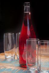 Soft drink bottle pink color served on table with empty glasses