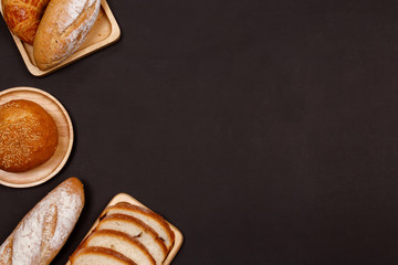 Homemade breads or bun, croissant and bakery ingredients, flour, almond nuts, hazelnuts, eggs on dark background, Bakery background frame, Cooking breakfast concept. Flat lay, Top view.
