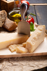 Traditional italian food - aged Italian parmesan hard cheese Parmigiano-Reggiano with cheese knife, tomato, basil, olive oil