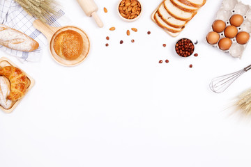 Homemade breads or bun, croissant and bakery ingredients, flour, almond nuts, hazelnuts, eggs on white background, Bakery background frame, Cooking breakfast concept. Flat lay, Top view and copy space