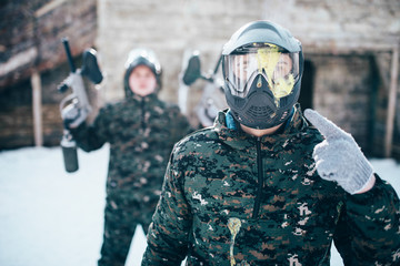 Paintball player points finger at splattered mask