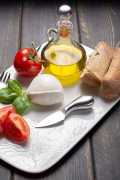 Traditional italian food - white ball mozzarella buffalo Italian soft cheese with cheese knife, tomato, basil, olive oil