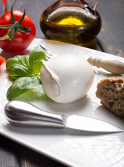 Traditional italian food - white ball mozzarella buffalo Italian soft cheese with cheese knife, tomato, basil, olive oil