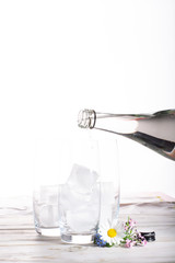 Pouring of still mineral drink water in glasses with ice cubes close up copy space