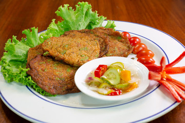 FFried fish meat mix spicy curry paste (Thai call Tod mun pla krai) eating with sauce pickles vegetables delicious thai food