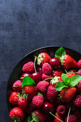 Fresh red ripe berries on black plate