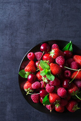 Fresh red ripe berries on black plate
