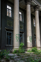 Naklejka premium DESTROYED FORMED OLD ADMINISTRATIVE HOUSE IN THE CITY ENVIRONMENT. REMAINS OF WALLS, STAIRS AND WINDOWS.