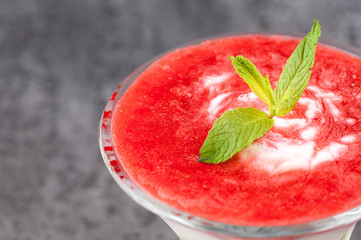 fruit smoothie with a petal in a glass vase on a gray surface.