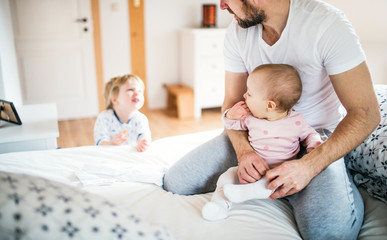 Father with toddler children in bedroom at home at bedtime.