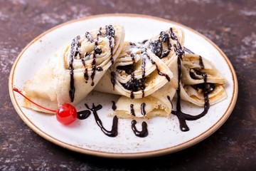 Pancakes with chocolate sauce. Sweet dessert on a plate