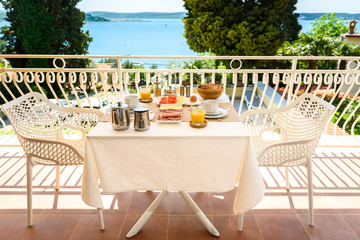 Continental morning breakfast table setting with sea view is served.