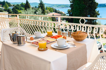 Continental morning breakfast table setting with sea view is served.