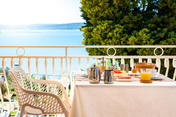 Continental morning breakfast table setting with sea view is served.
