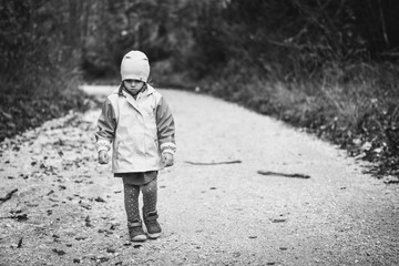 Young sad girl child is walking alone on country road.