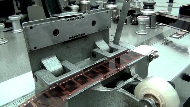 Man cutting film on Retro Machine cutter for movie film