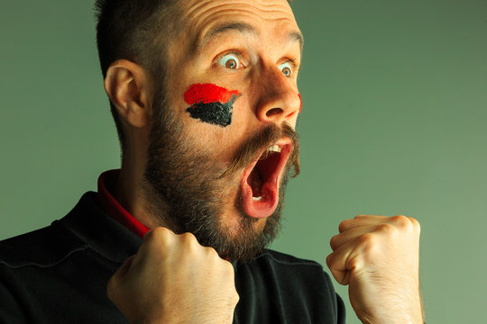 Portrait of a man with the flag of the Germany painted on him face.