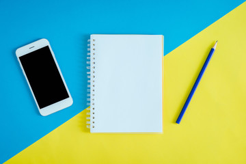 High Angle View Of Mobile Phone With Note Pad And Pencil Over Colored Background