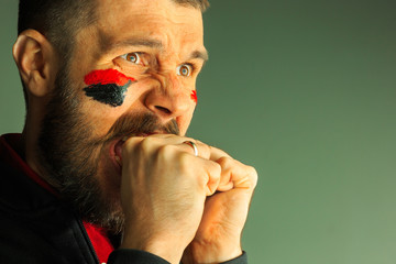 Portrait of a man with the flag of the Germany painted on him face.