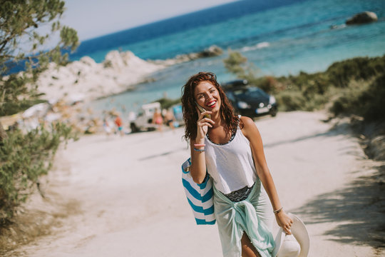 Pretty Young Woman With A Bag Using Mobile Phone On The Beach